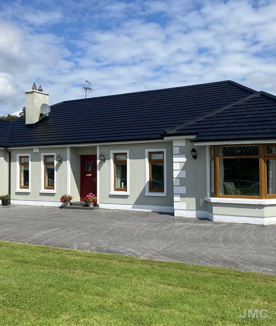 A bungalow with a cleaned roof and drive under a blue sky